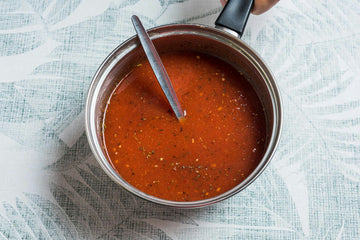 In a pot, mix together **crushed tomatoes**, **vegetable broth**, a glass of **water**, and season with **Mediterranean herbs**, **salt**, **pepper**, and **sugar**. 
