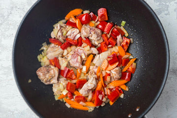 Add **bell peppers, onions** and **carrots** to the pan and fry for **2 minutes**. Then add the **tomato paste** and fry for a **few more minutes**.
