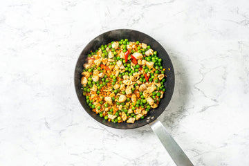 Place the **chicken** in a pan and cook for another 3 minutes, then add the chopped **carrots** and **frozen** **peas**.
